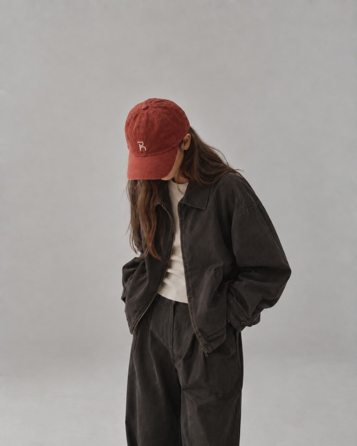 plain. house — 브릭 레드 캡과 느슨한 차콜 재킷·팬츠를 입은 모델