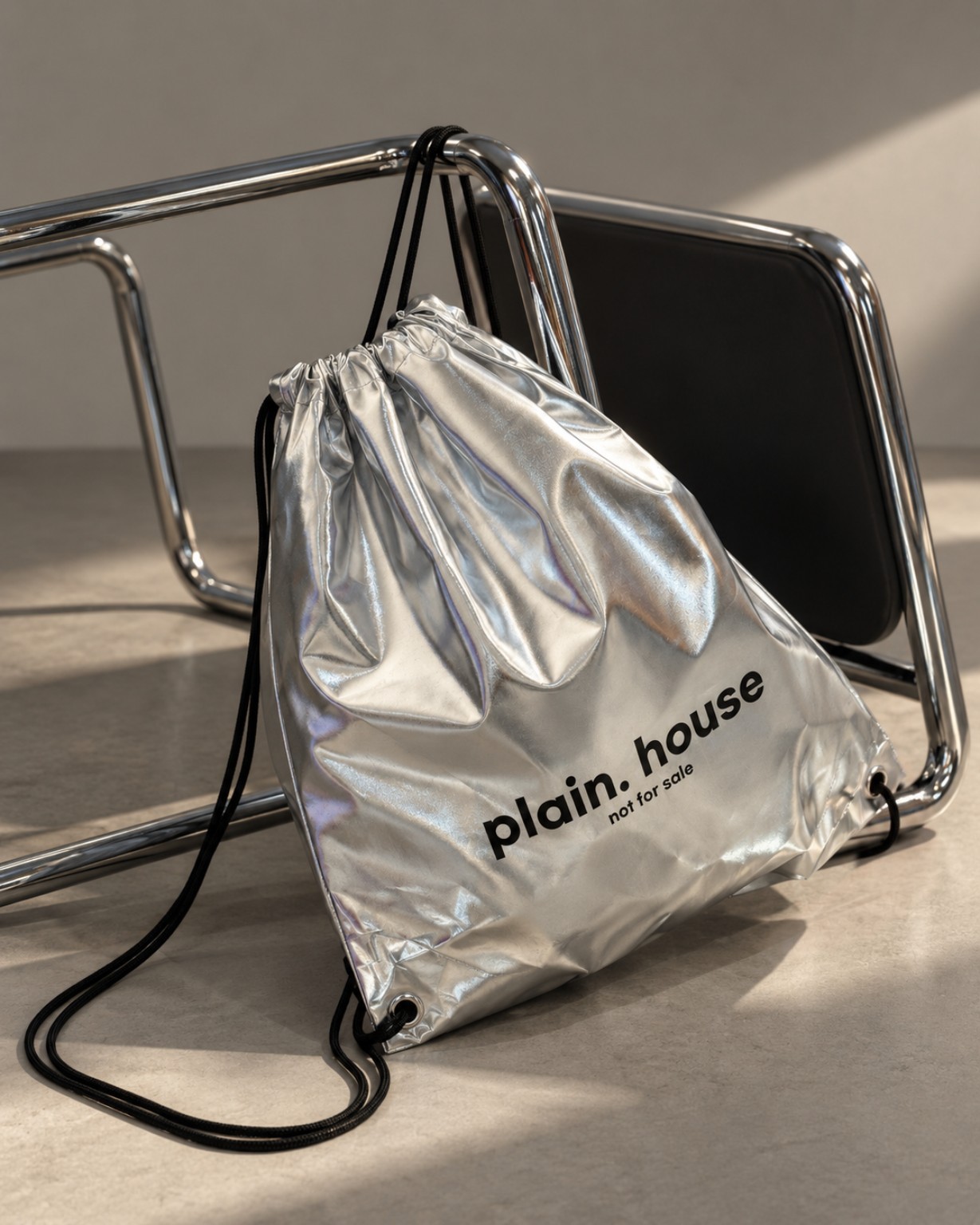 plain. house NOT FOR SALE — 금속 의자에 걸쳐 놓인 은색 스트링 백
